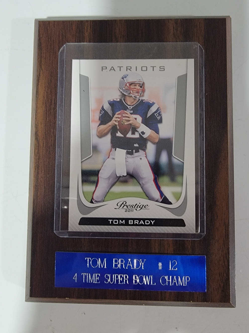 Tom Brady football card on a wooden plaque.